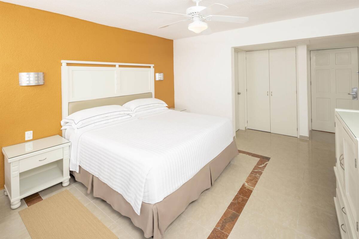 Un dormitorio con cama, mesita de noche, cómoda y armario.