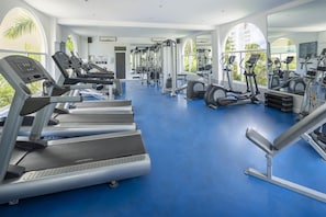 Un gimnasio con cintas de correr, elípticas y equipo de pesas.
