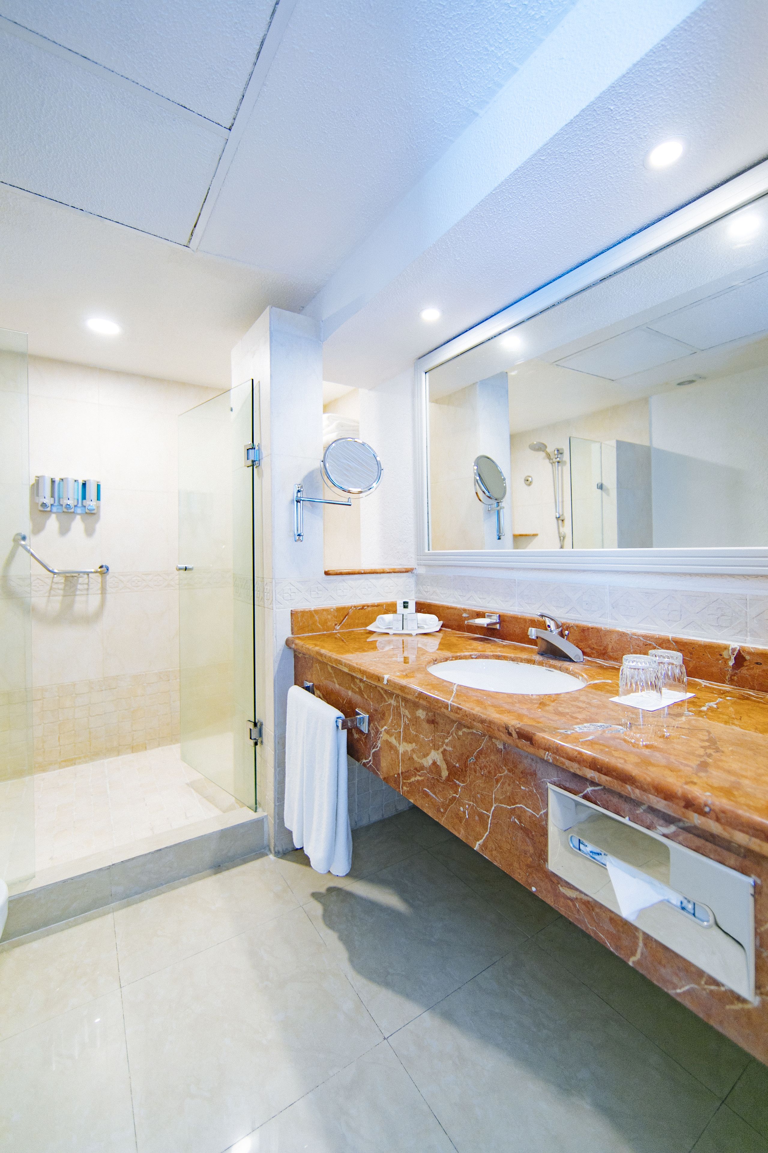 A modern bathroom with a glass-enclosed shower, a marble sink, and a large mirror.