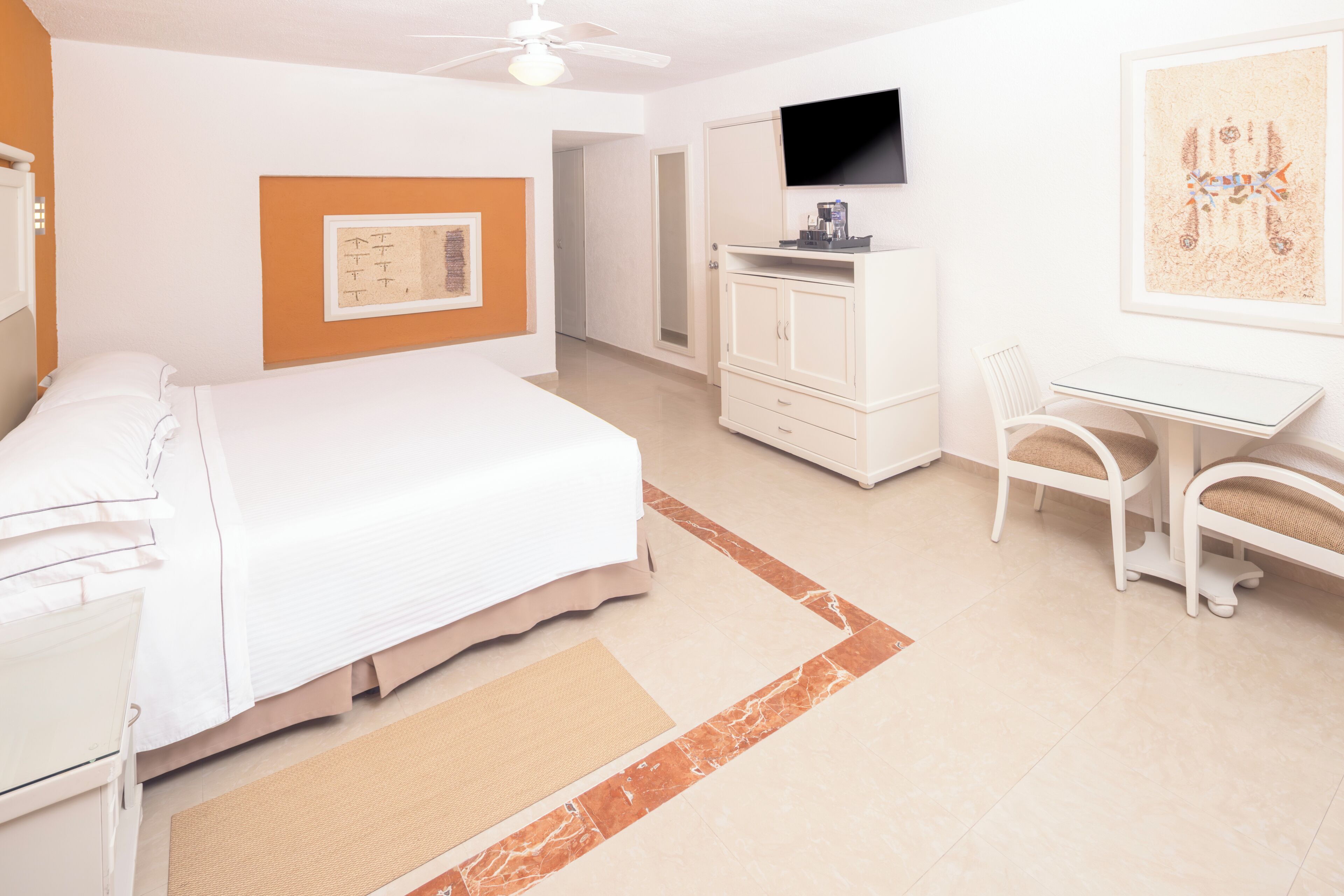 A hotel room with a bed, a desk, a chair, a television, and a framed picture on the wall.