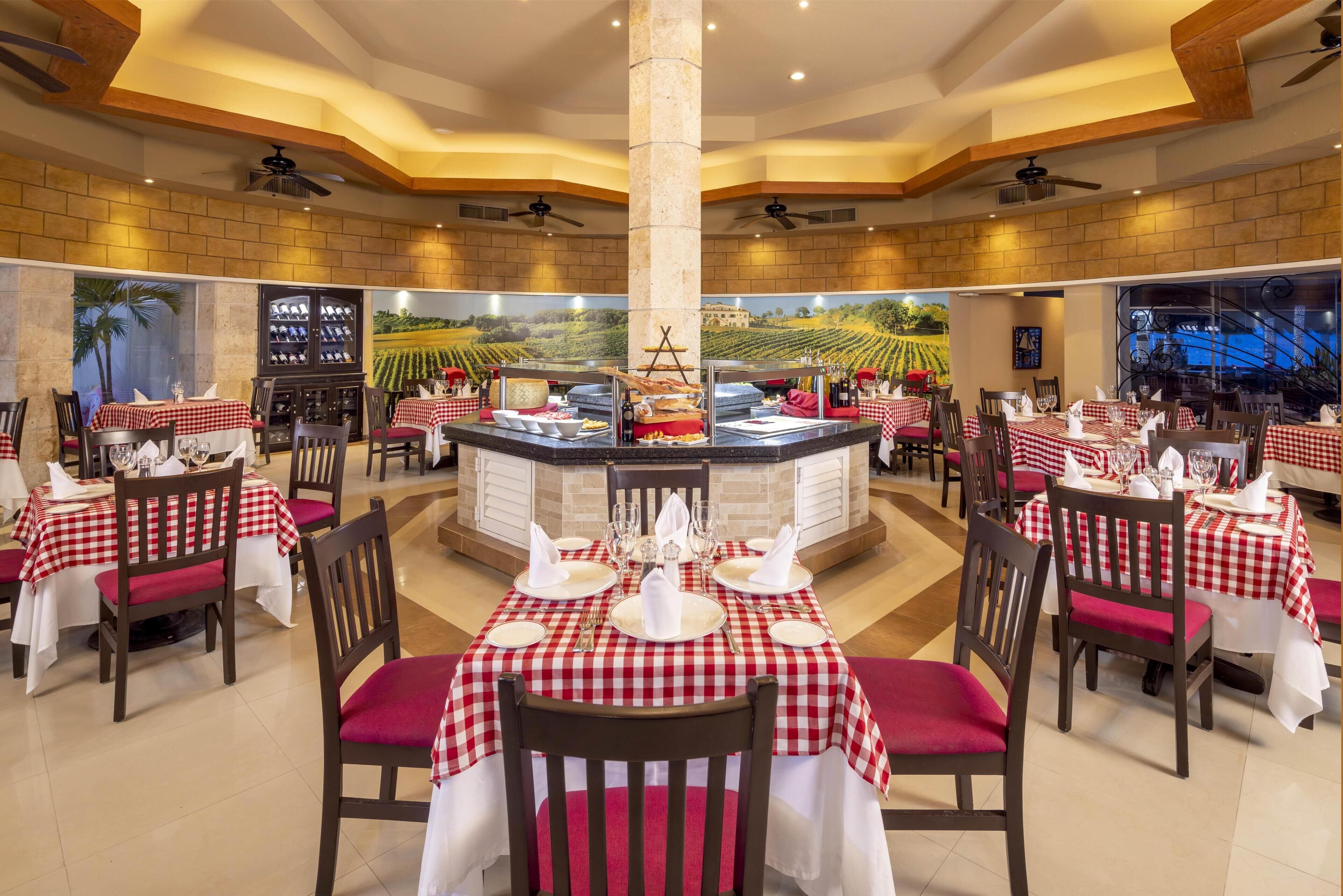 A restaurant with checkered tablecloths, wooden chairs, and a central bar area.