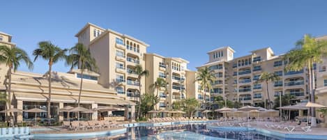 Un hotel con varias edificaciones, piscina y palmeras.