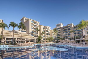 Una piscina al aire libre, sombrillas, sillones reclinables de piscina
