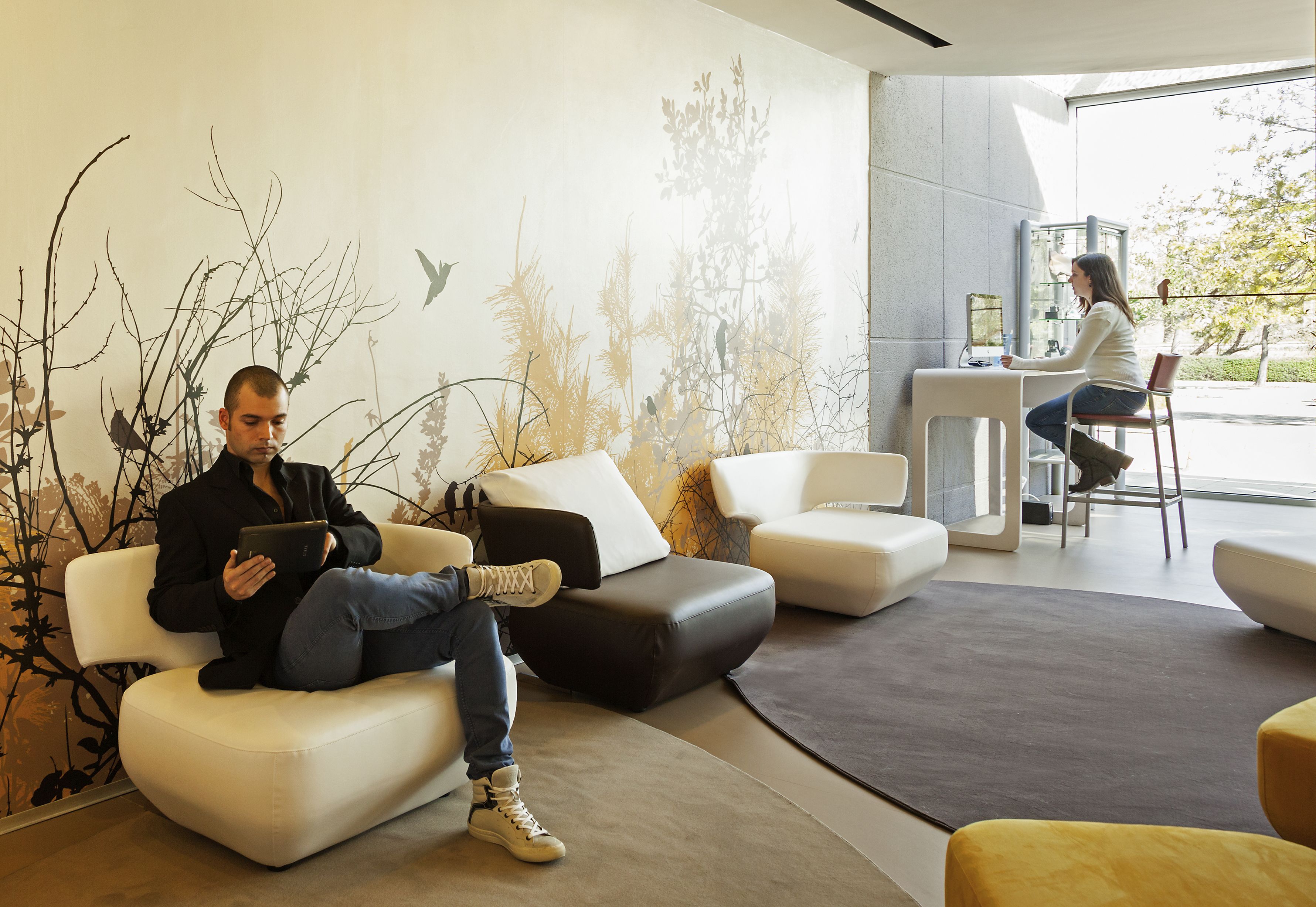 Interior moderno com área de estar, divisória de vidro e vista para o exterior.