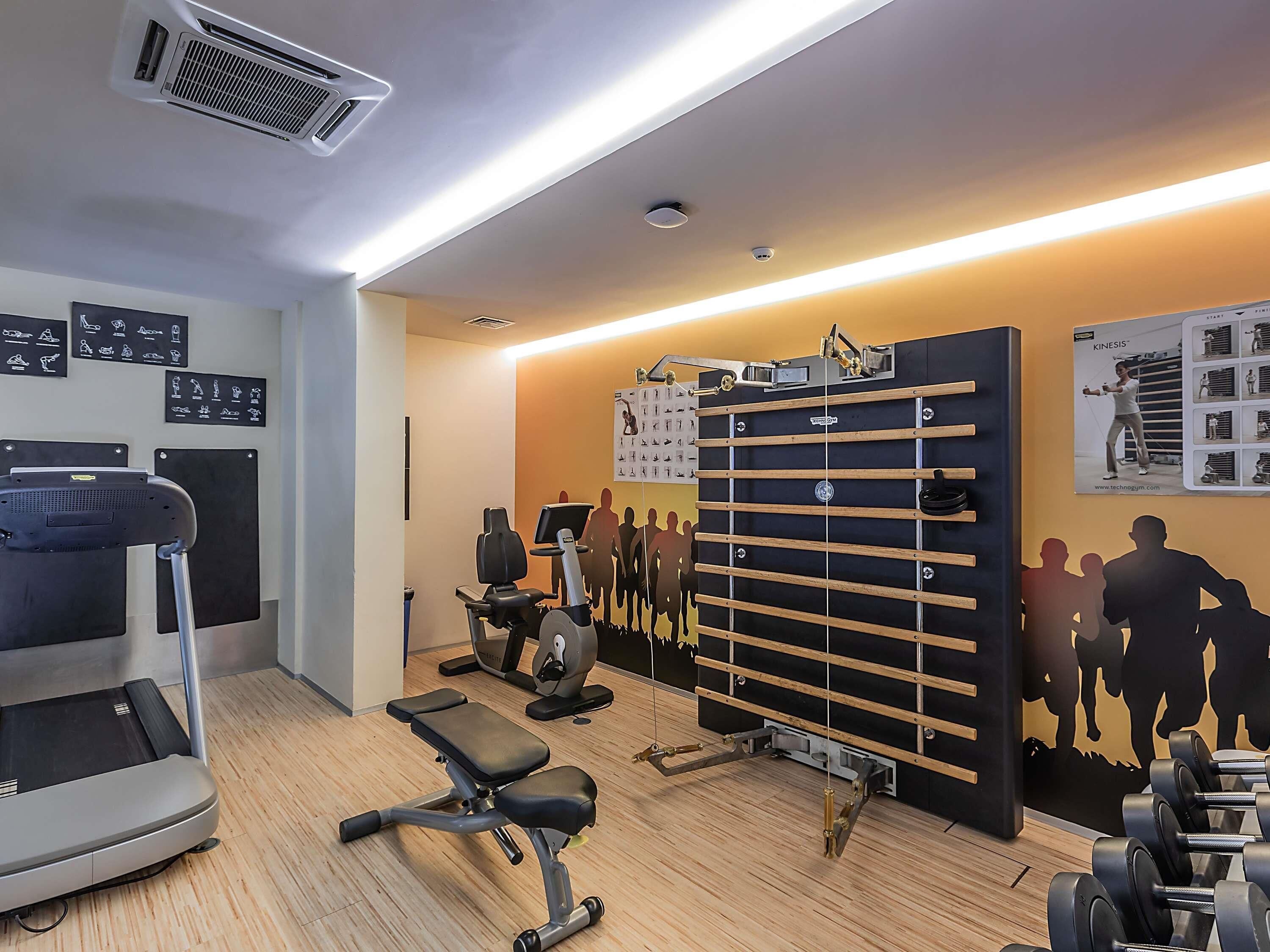 A gym with exercise equipment, a wall-mounted rack, and a treadmill.