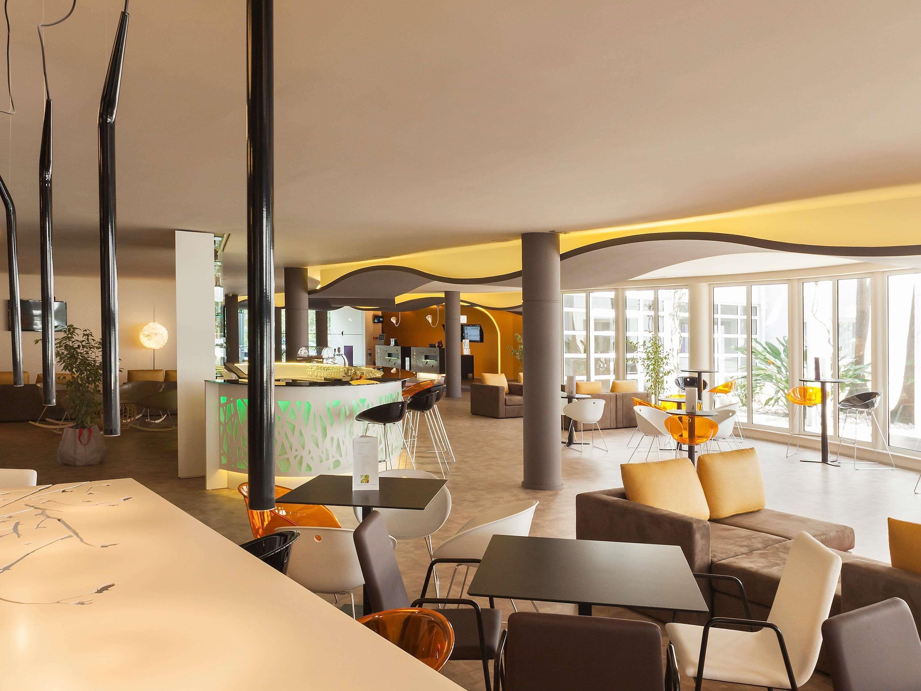A modern hotel lobby with a reception desk, seating areas, and large windows.