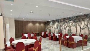A conference room with round tables, red chairs with yellow sashes, and a marble floor.