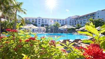 Un resort con piscina, tumbonas y palmeras.