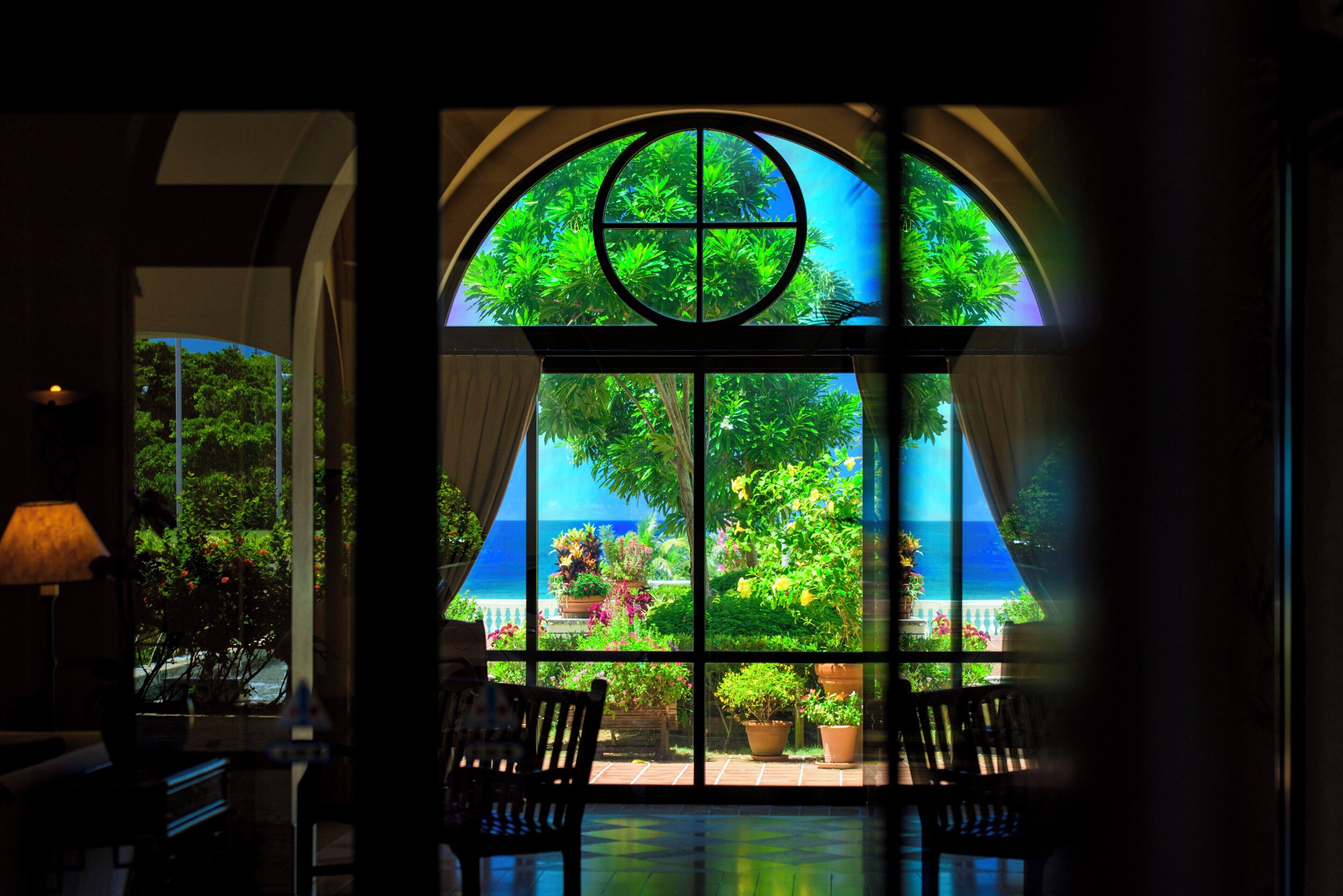A room with a large arched window, a bench, and a lamp.