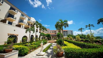 A courtyard with a statue, palm trees, and a pool.