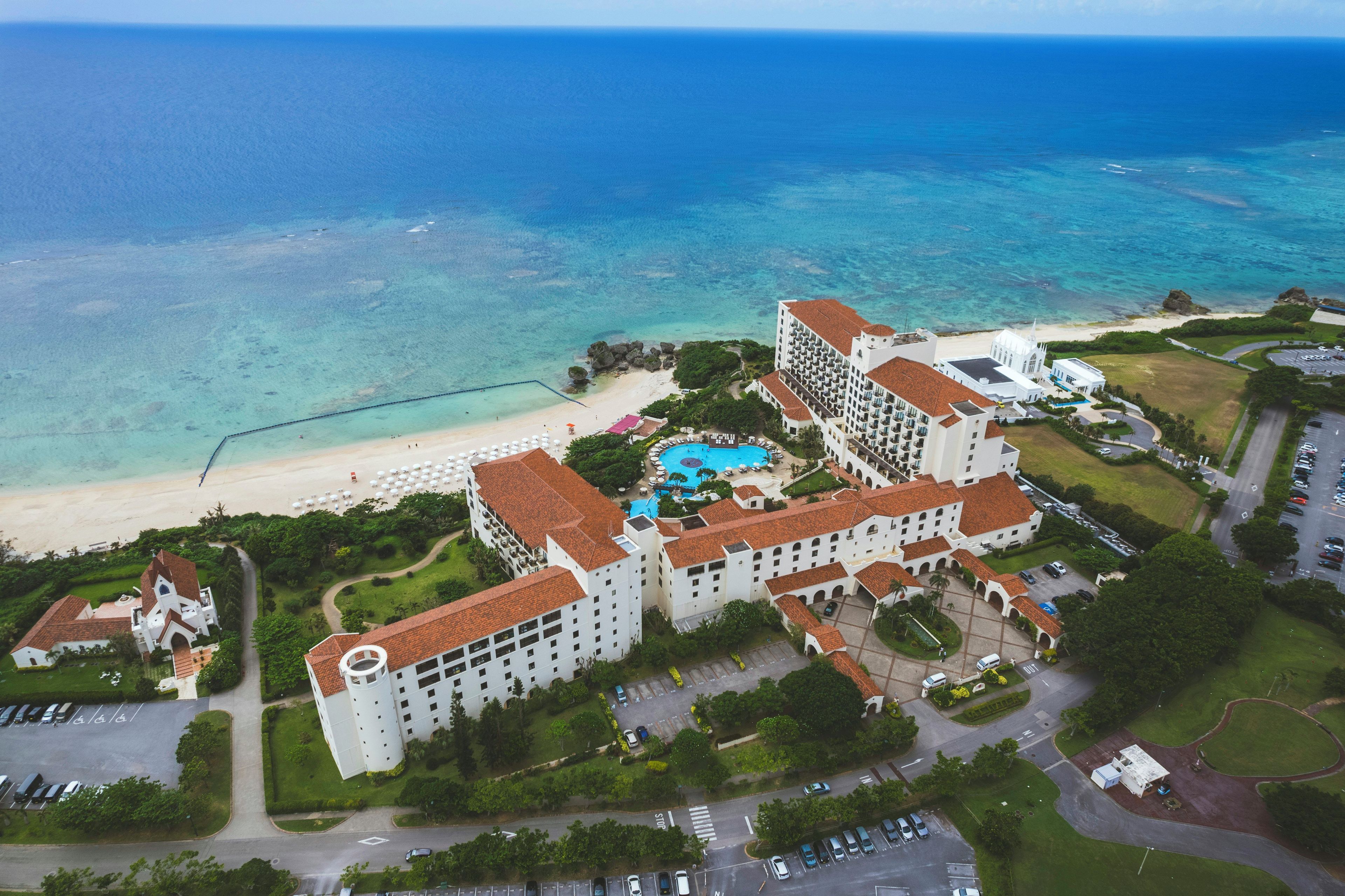 A resort with multiple buildings, a beach, and a swimming pool.