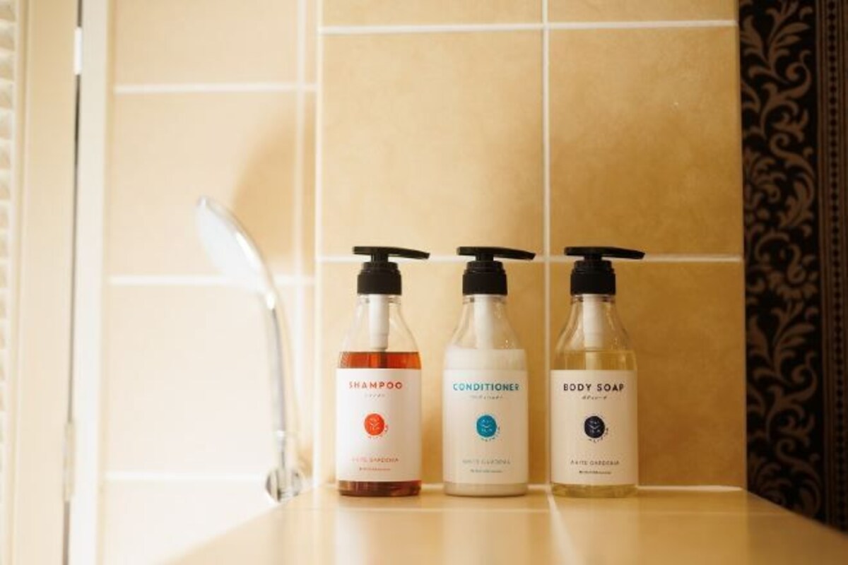 Tres botellas de champú, acondicionador y jabón de baño sobre una encimera de baño.