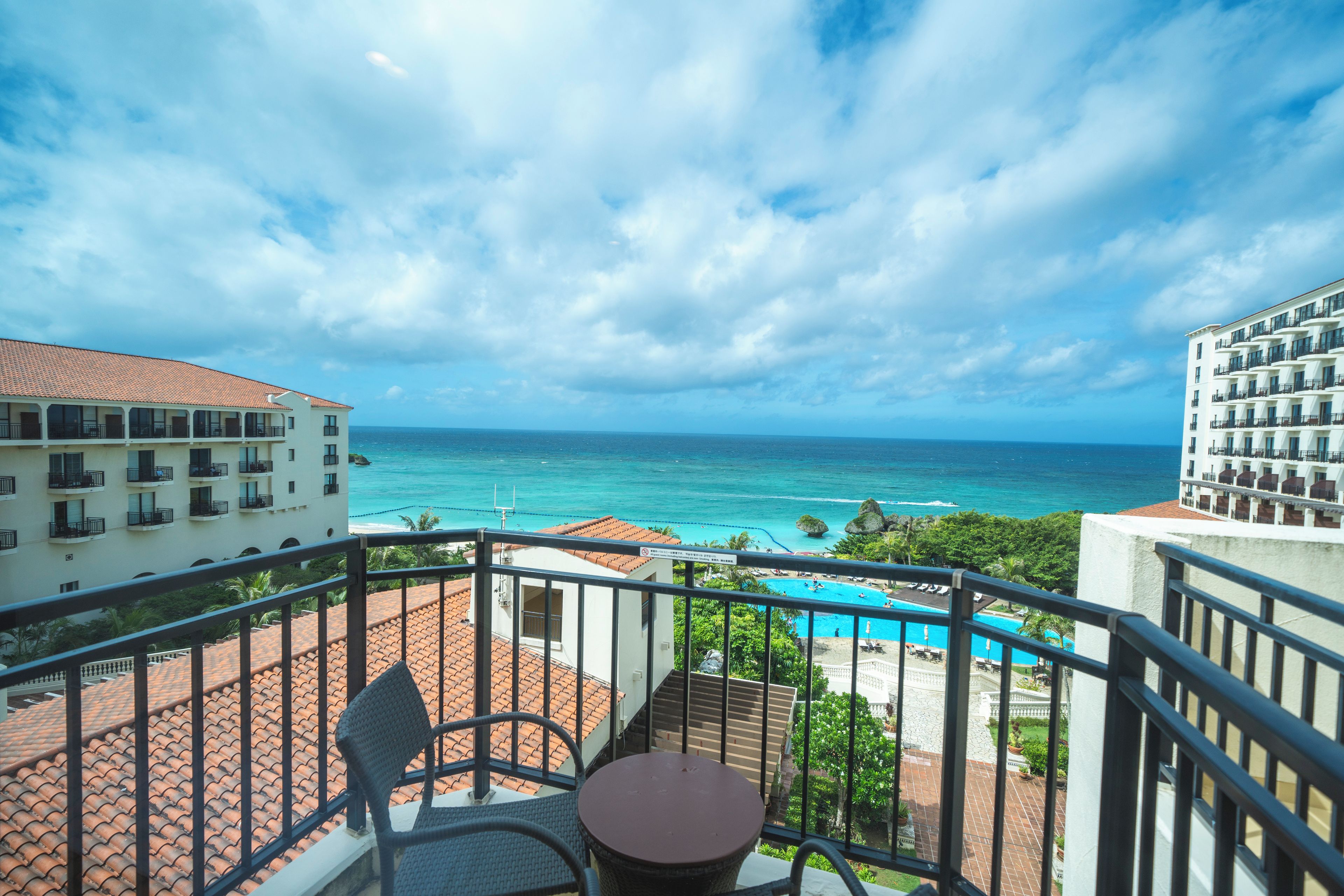 A balcony with a view of the ocean and a swimming pool.