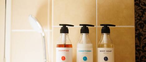 Three bottles of White Gardenia shampoo, conditioner, and body soap on a bathroom counter.