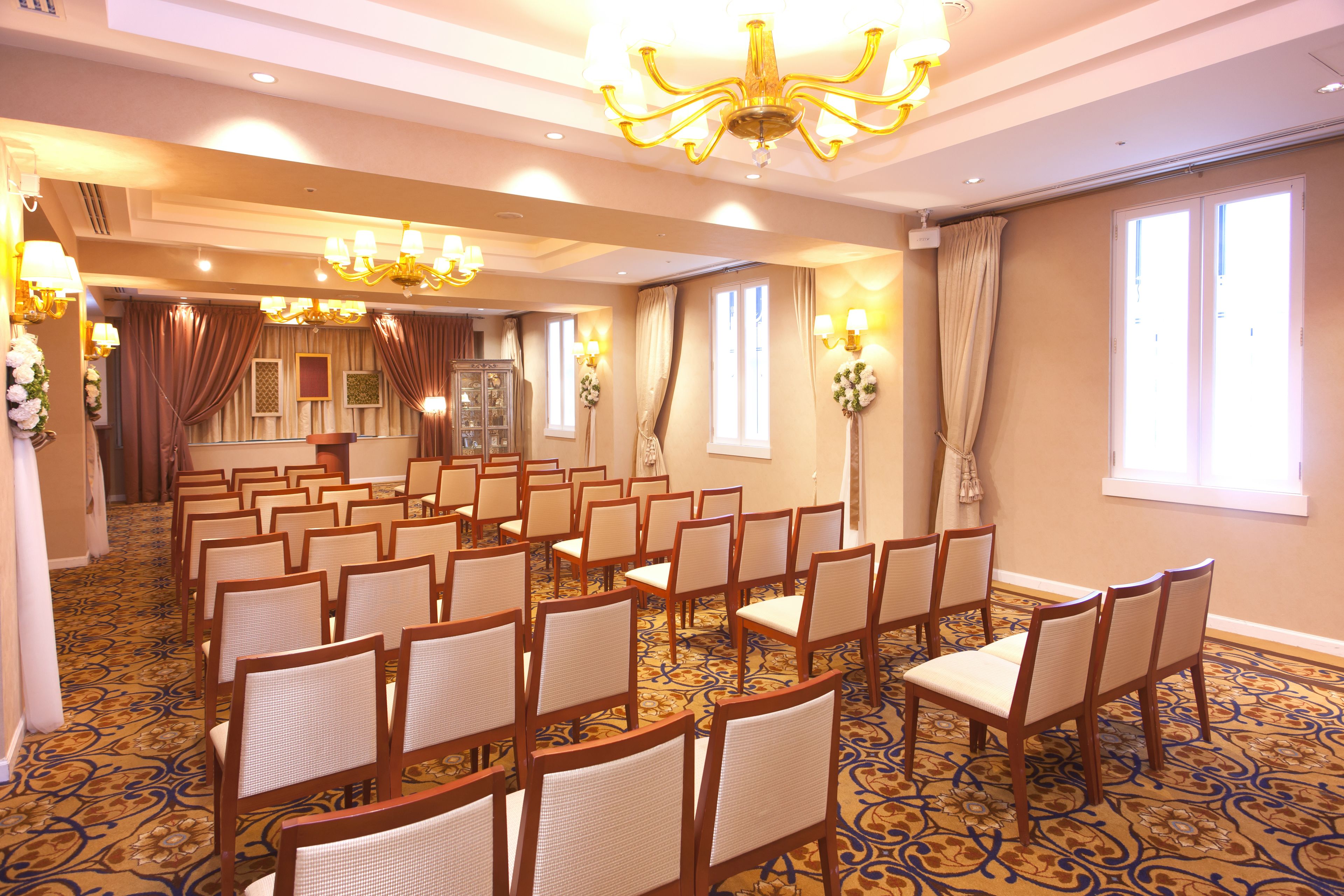 A conference room with rows of chairs, a podium, and a chandelier.