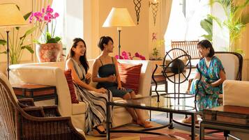 Un grupo de personas sentadas en una habitación bien iluminada, con un sofá, sillas y una mesa.