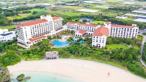 Un resort con varias construcciones, piscina y playa.