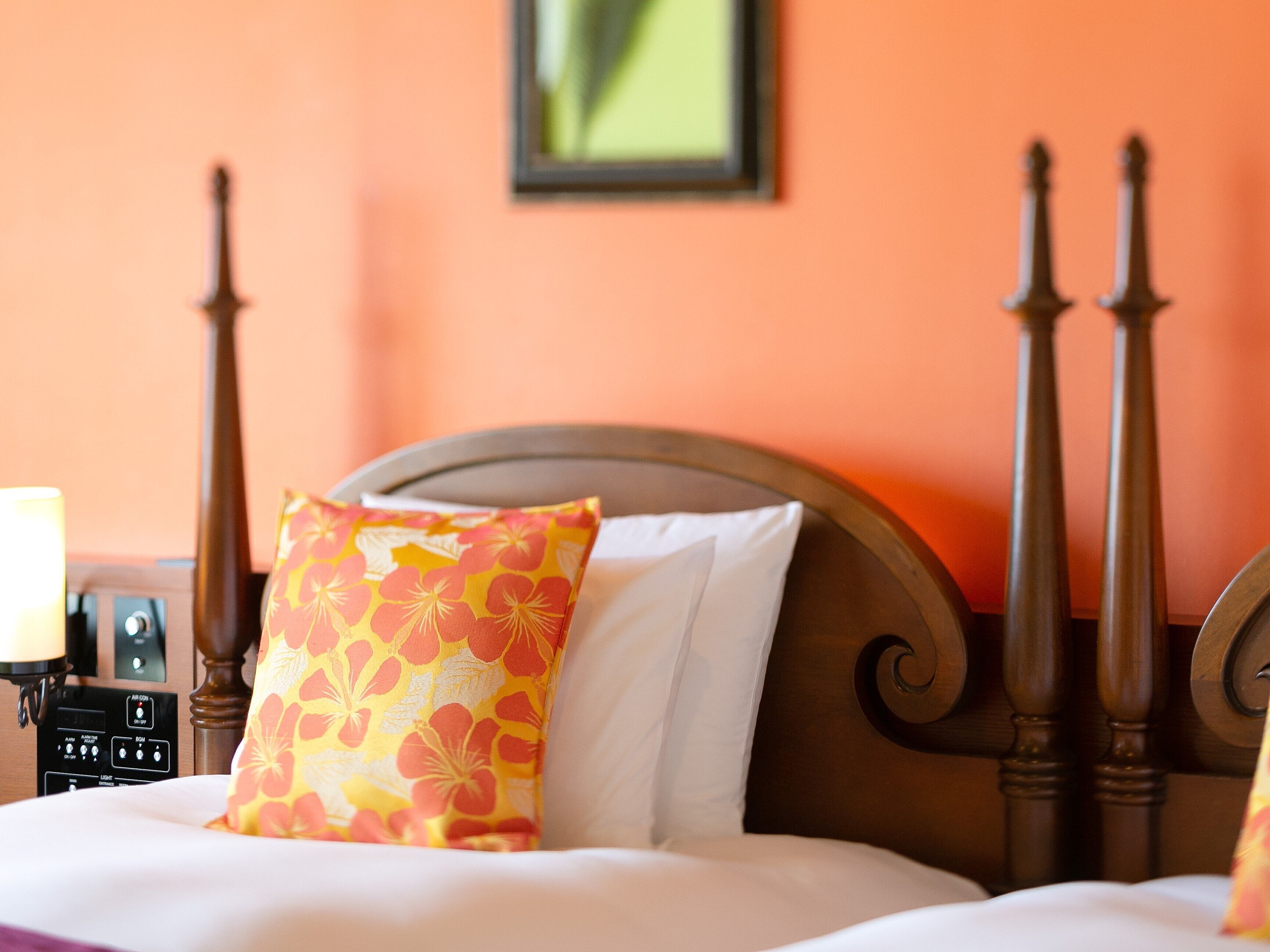 A bed with a wooden headboard, a floral pillow, and a bedside table with a lamp.