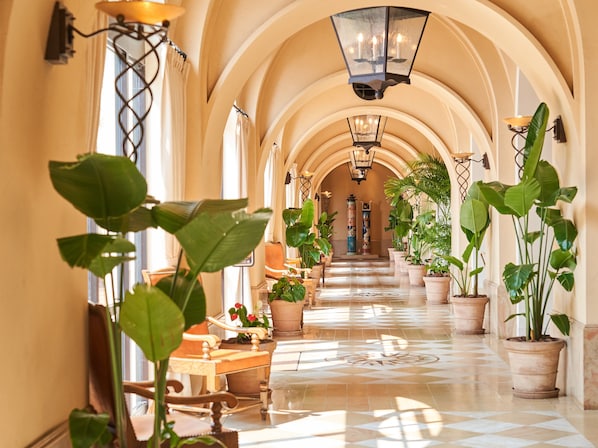 A hallway with arches, potted plants, and a chandelier. - Hotel Nikko Alivila (Yomitan)