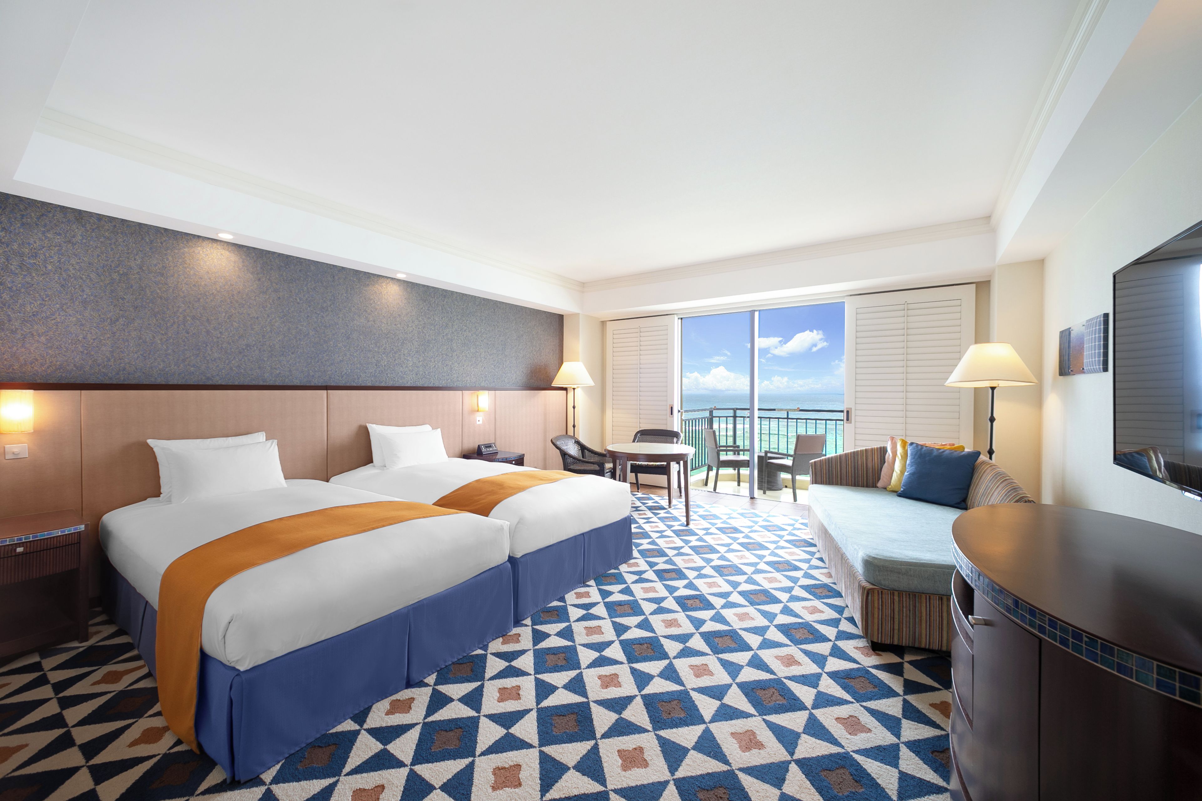 Una habitación de hotel con una cama grande, un sofá, una mesa de comedor y un balcón con vistas.