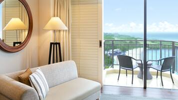 A hotel room with a sofa, two lamps, a mirror, and a balcony with outdoor furniture.
