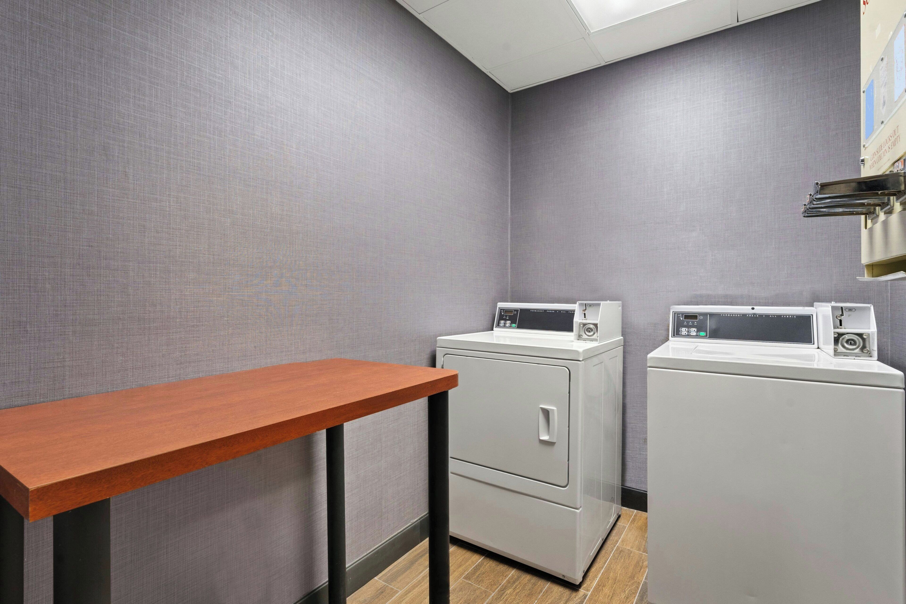 A laundry room with two washing machines and a wooden table.