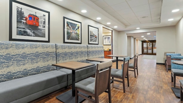 A restaurant with booths, tables, and framed pictures on the wall. - Elgin Inn (Elgin)