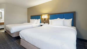 A hotel room with two beds, a nightstand with a lamp, and a bathroom visible in the background. - Elgin Inn (Elgin)