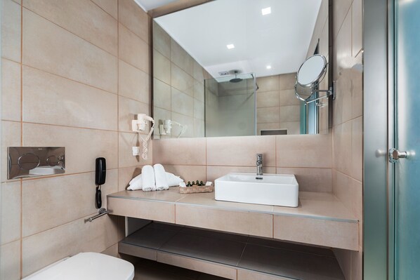 Une salle de bain moderne avec un lavabo blanc, une douche en verre et un miroir.
