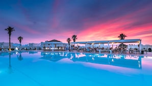 A poolside area with lounge chairs and umbrellas, a bar, and a sunset view. - Aeolos Beach Hotel (Kos)
