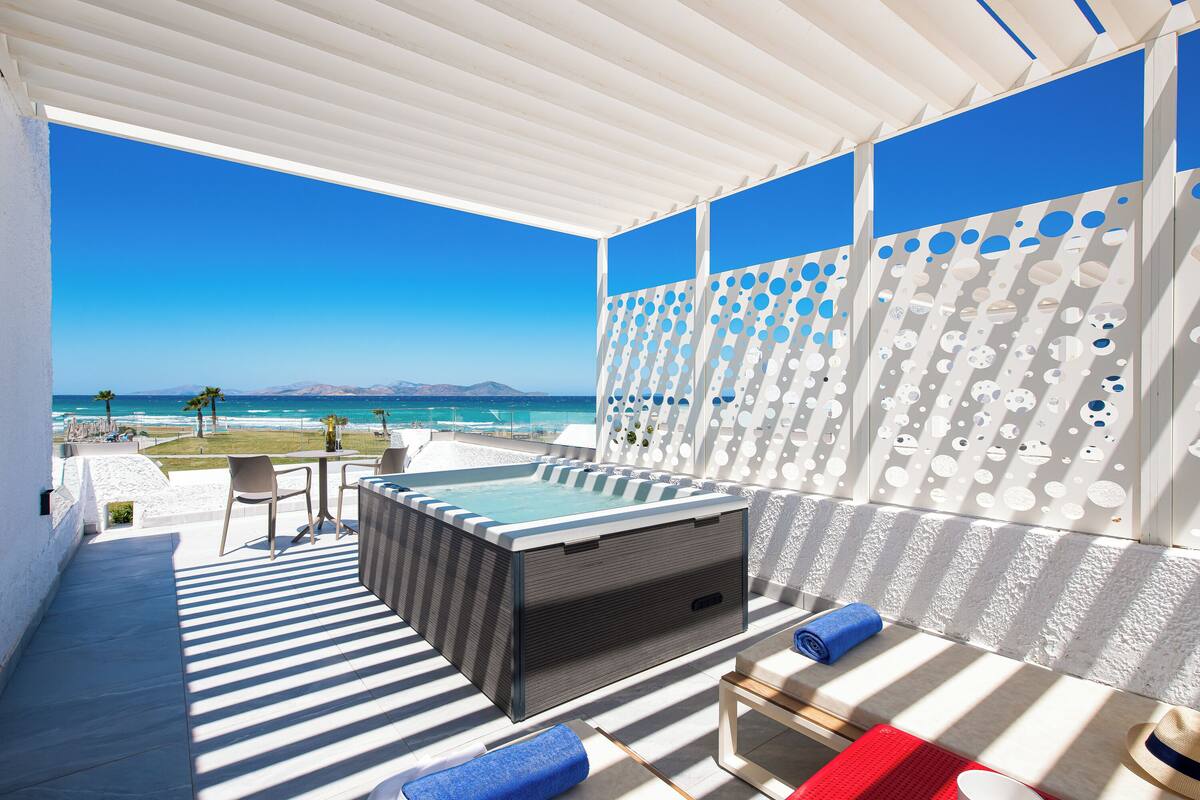 A modern outdoor lounge area with a hot tub, striped flooring, and a view of the ocean.