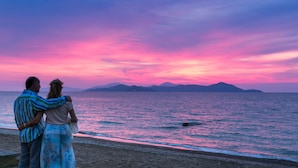 A couple standing on a beach with a sunset in the background. - Aeolos Beach Hotel (Kos)