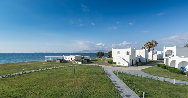 A coastal hotel with white architecture, a paved walkway, and a view of the sea. - Aeolos Beach Hotel (Kos)