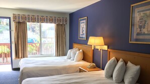 A hotel room with two beds, a window with curtains, a bedside lamp, and a framed picture on the wall. - Bay Inn and Suites at Seaworld (San Diego)