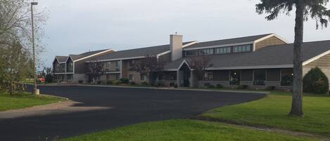 A multi-story residential building with a central entrance, a covered porch, and a driveway leading to the parking area.