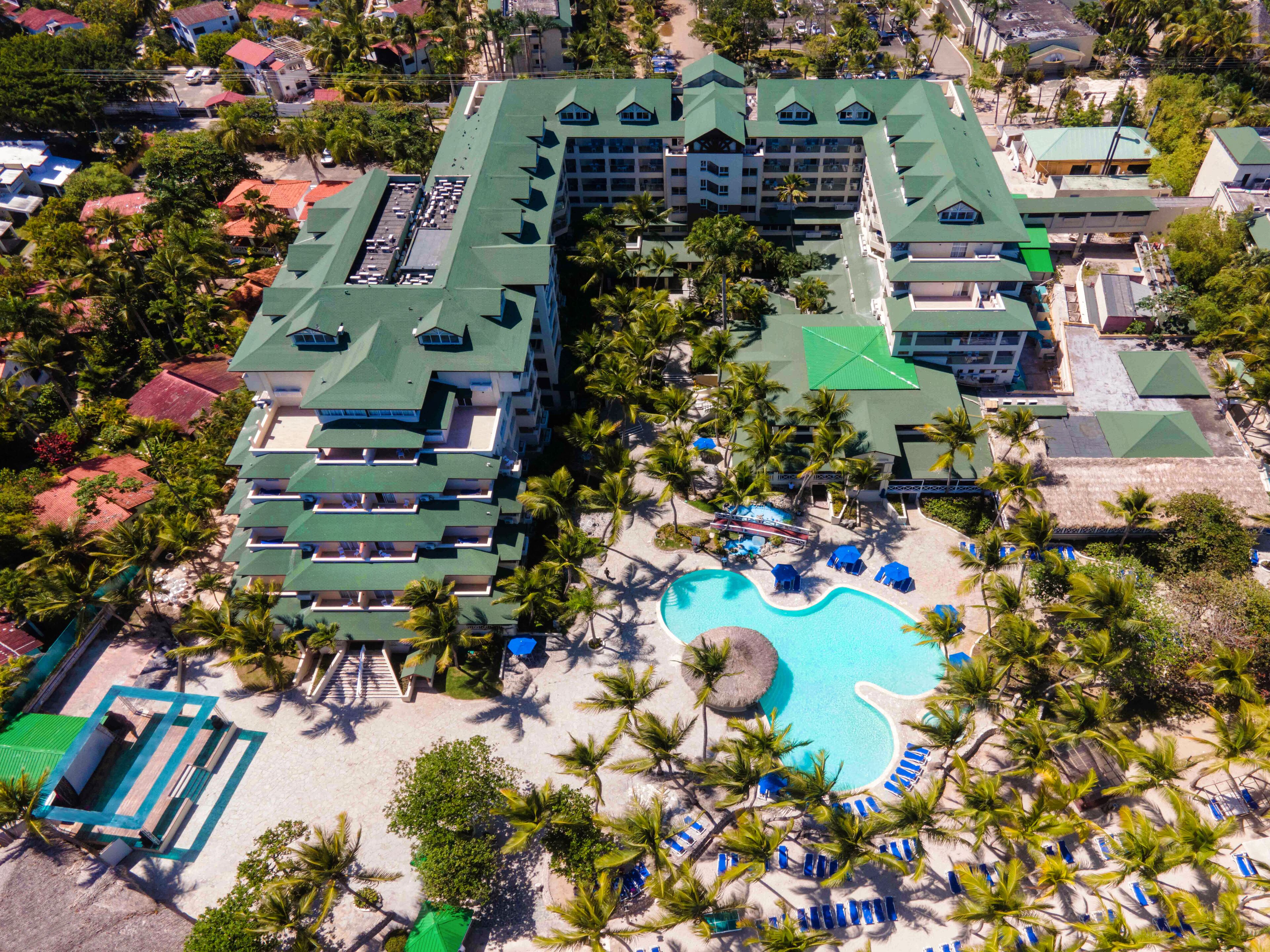 Vista aerea di un resort con diversi edifici, una piscina e palme.