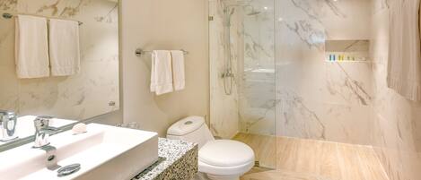 A modern bathroom with a marble sink, a toilet, and a glass-enclosed shower.