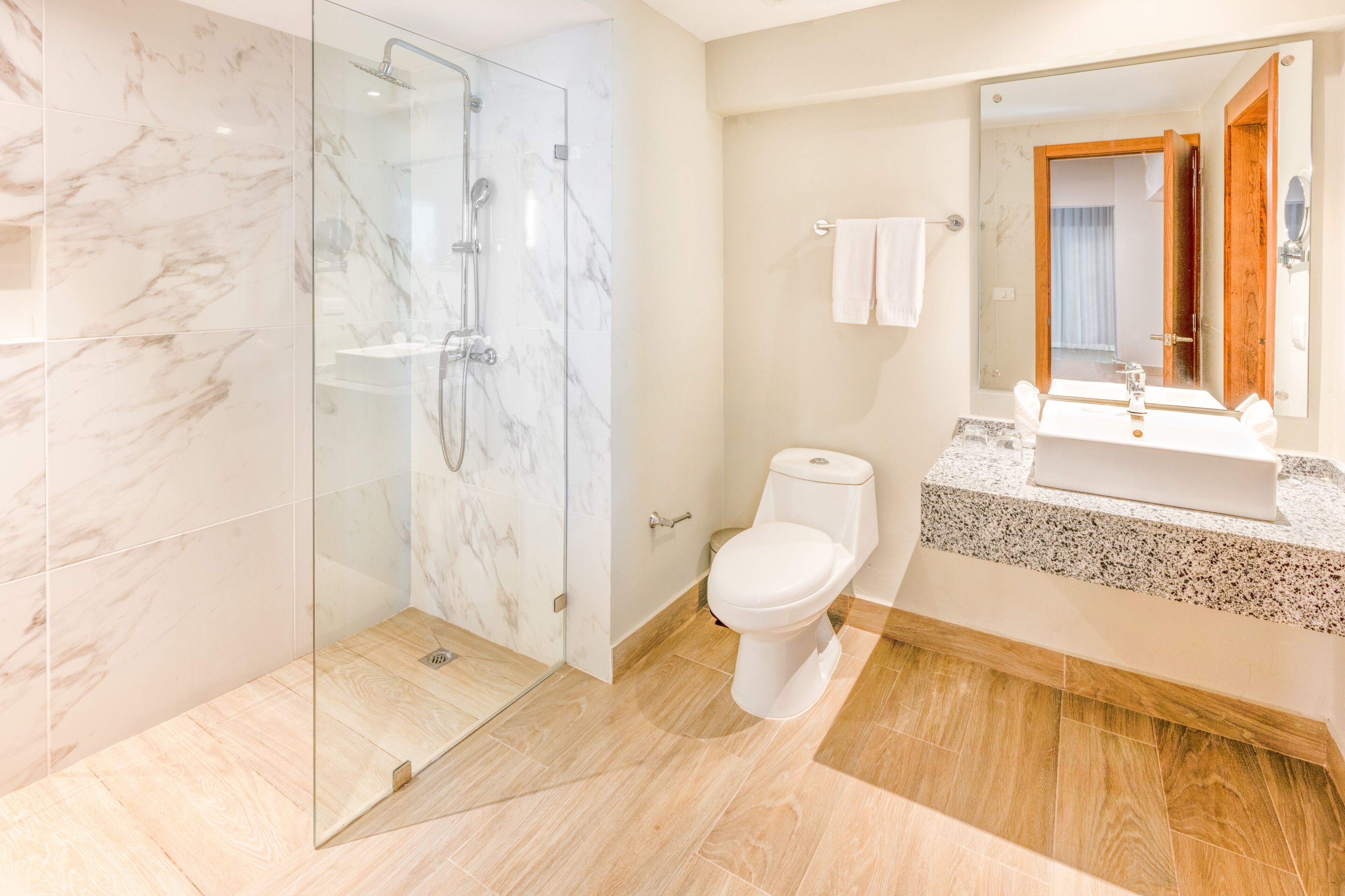Une salle de bain moderne dotée d’une douche à parois de verre, de toilettes et d’un lavabo avec un plan de travail en granit.