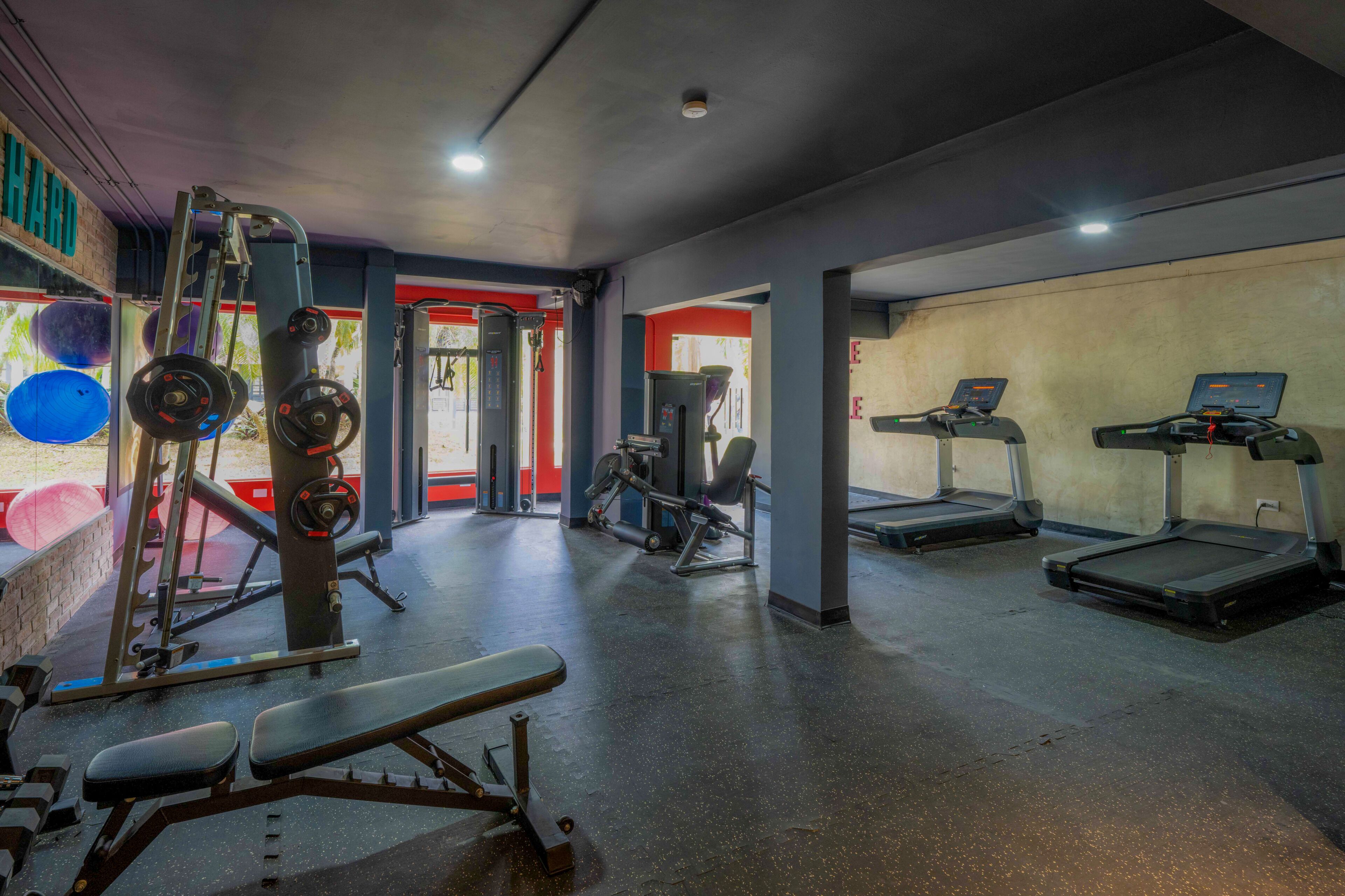 Un gimnasio con equipo de ejercicio, cintas de correr y una banca de pesas.