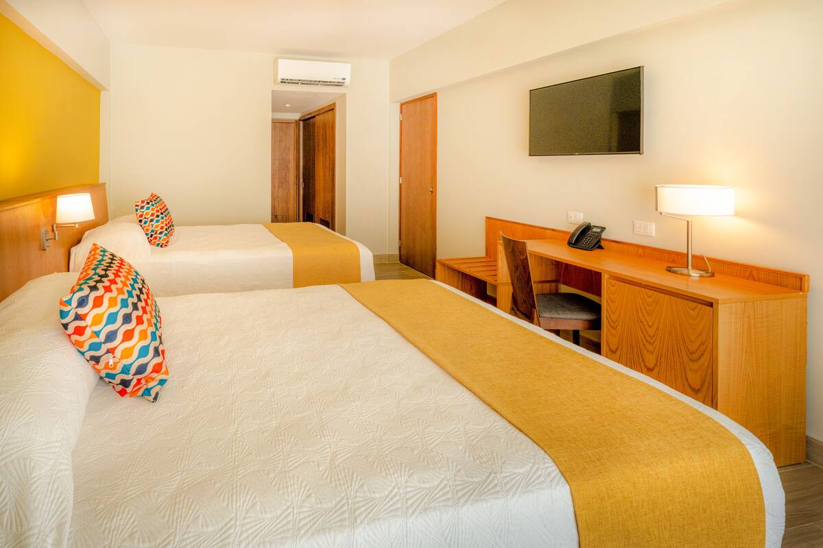 Une chambre d’hôtel avec deux lits, un bureau, une chaise, une télévision et un téléphone.