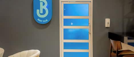 Ein Raum mit einer Tür, einem an der Wand befestigten Schild, das 'Bachata Night Club' zeigt, und zwei Stühlen.