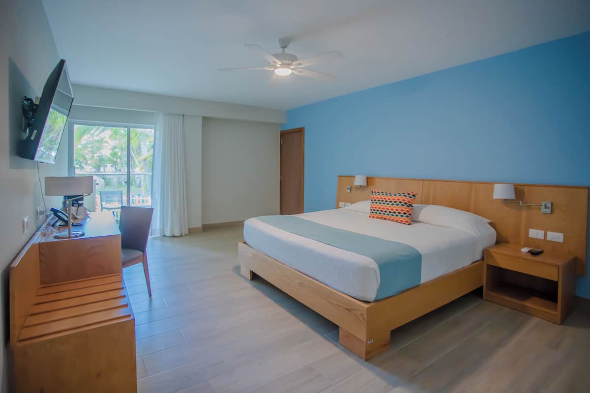 Une chambre d’hôtel moderne équipée d’un lit, d’un bureau, d’une chaise et d’un téléviseur fixé au mur.