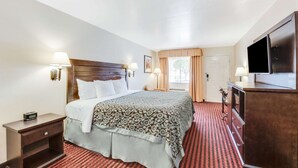 A hotel room with a large bed, a TV, a dresser, and a nightstand. - Days Inn by Wyndham Fort Stockton (Fort Stockton)