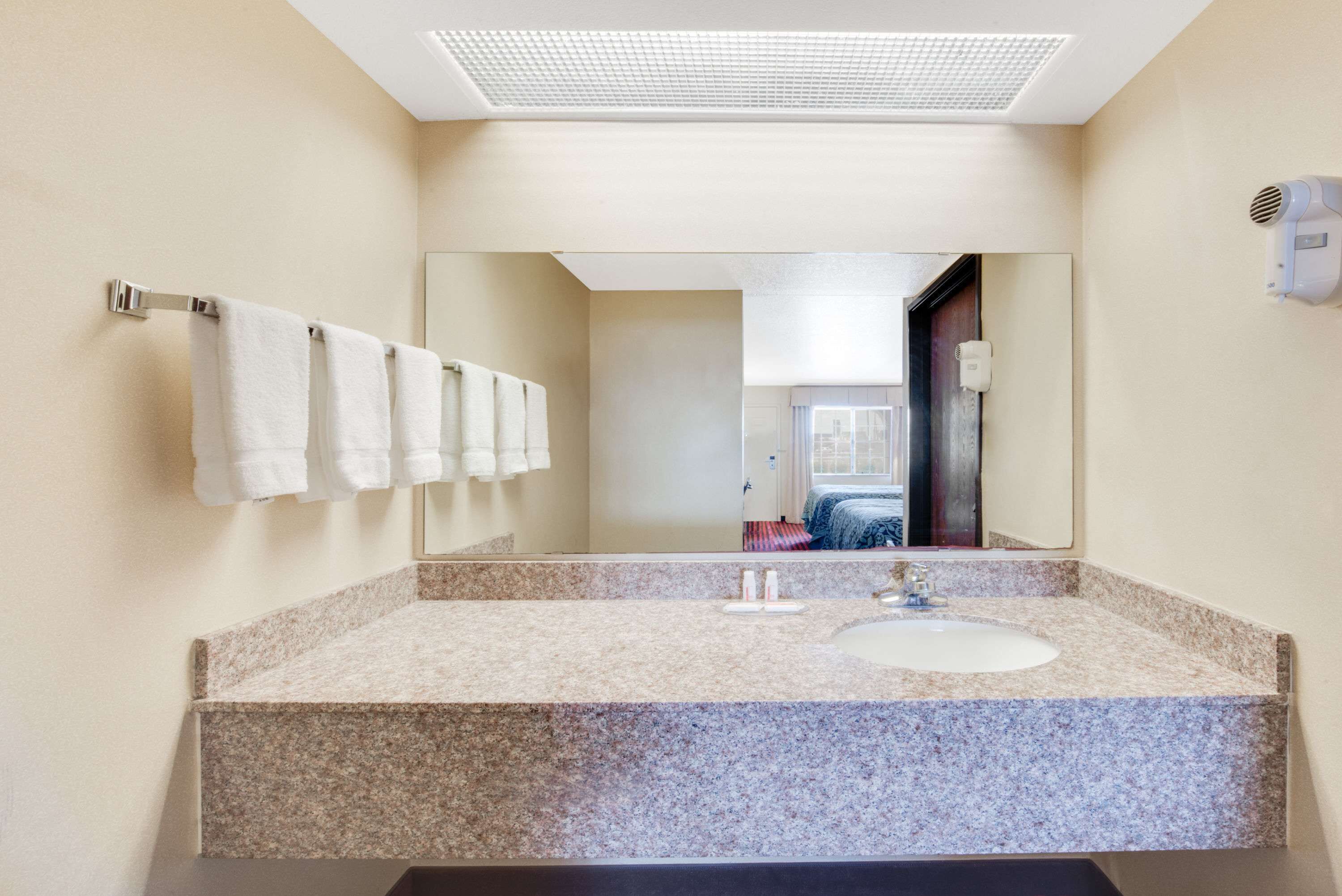 A modern bathroom with a granite countertop, a white sink, and a large mirror.