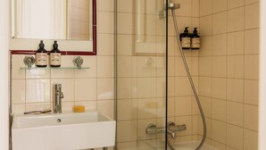 A bathroom with a sink, mirror, and shower. - Hôtel Blanca (Paris)