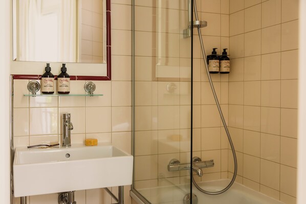 A bathroom with a sink, mirror, and shower. - Hôtel Blanca (Paris)
