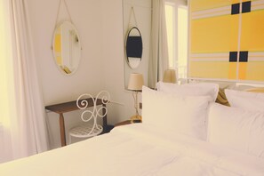 Ett hotellrum med en säng, två sängbord, en spegel och ett fönster med gardiner.