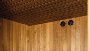 A wooden sauna with benches, a bucket, and a towel. - Hôtel Blanca (Paris)