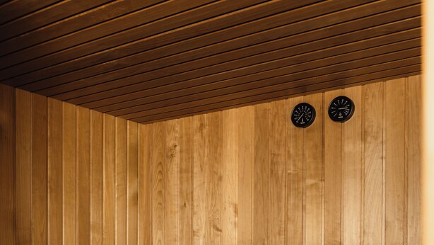 A wooden sauna with benches, a bucket, and a towel.