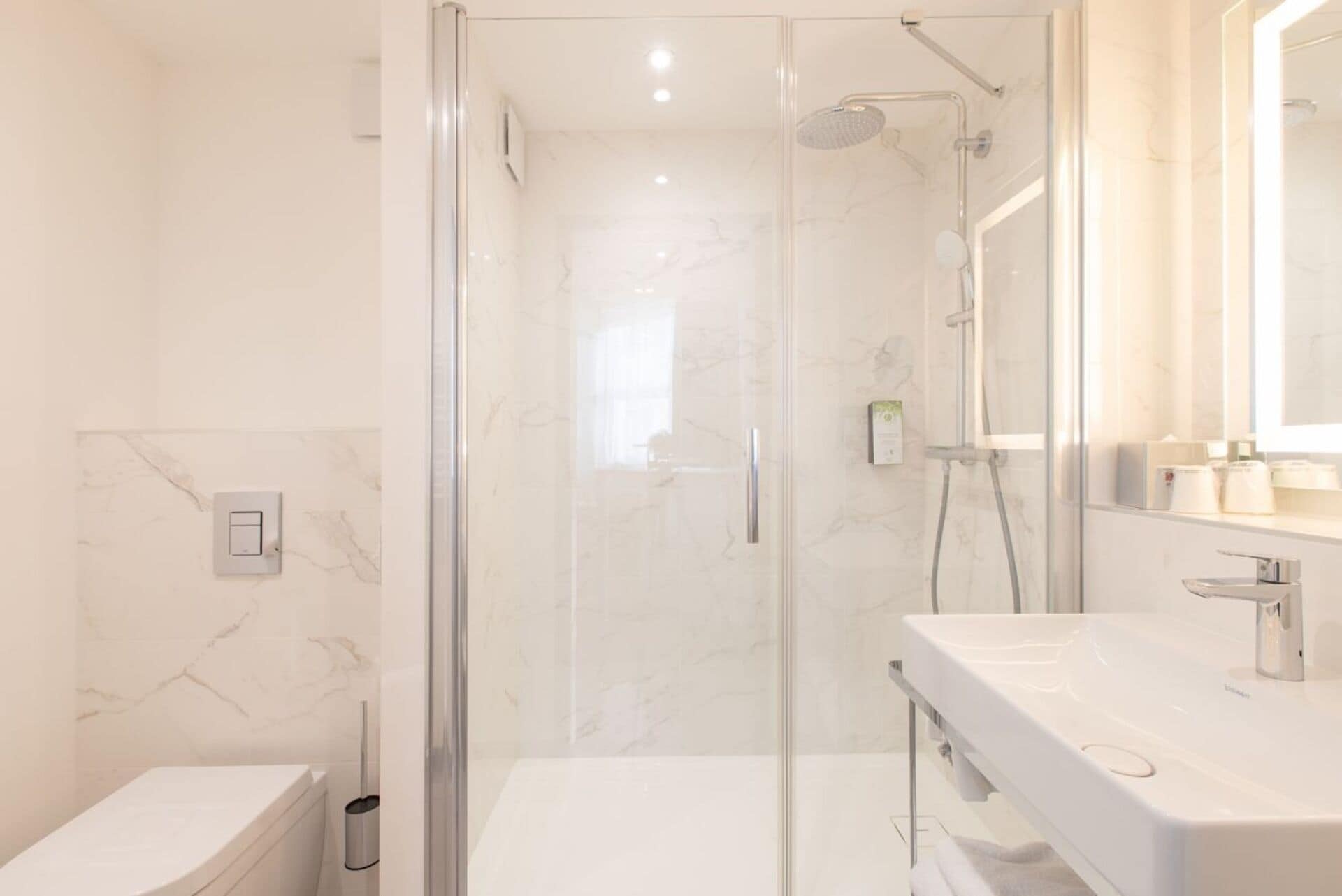 A modern bathroom with a glass-enclosed shower, a white toilet, and a vanity with a mirror.